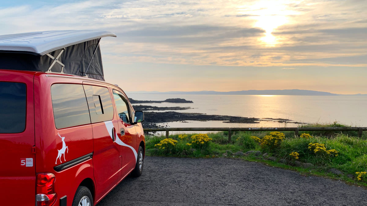 Red campervan overlooking sunset along the Causeway Coast Way