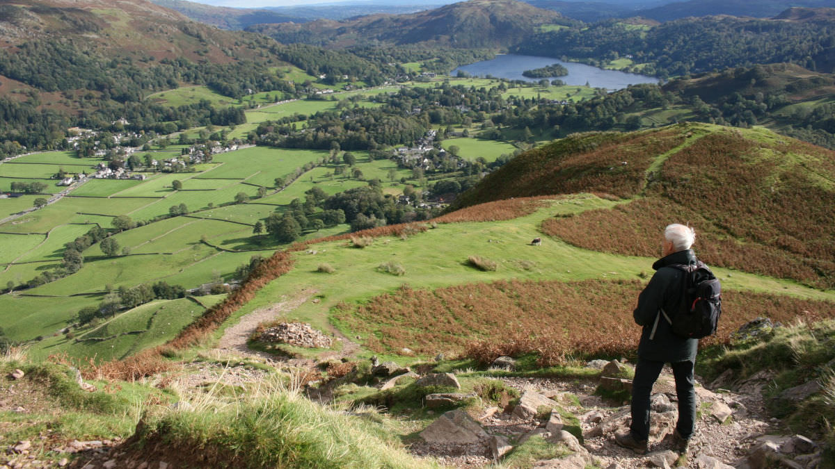 Walker overlooking grassy valley in the Lake District